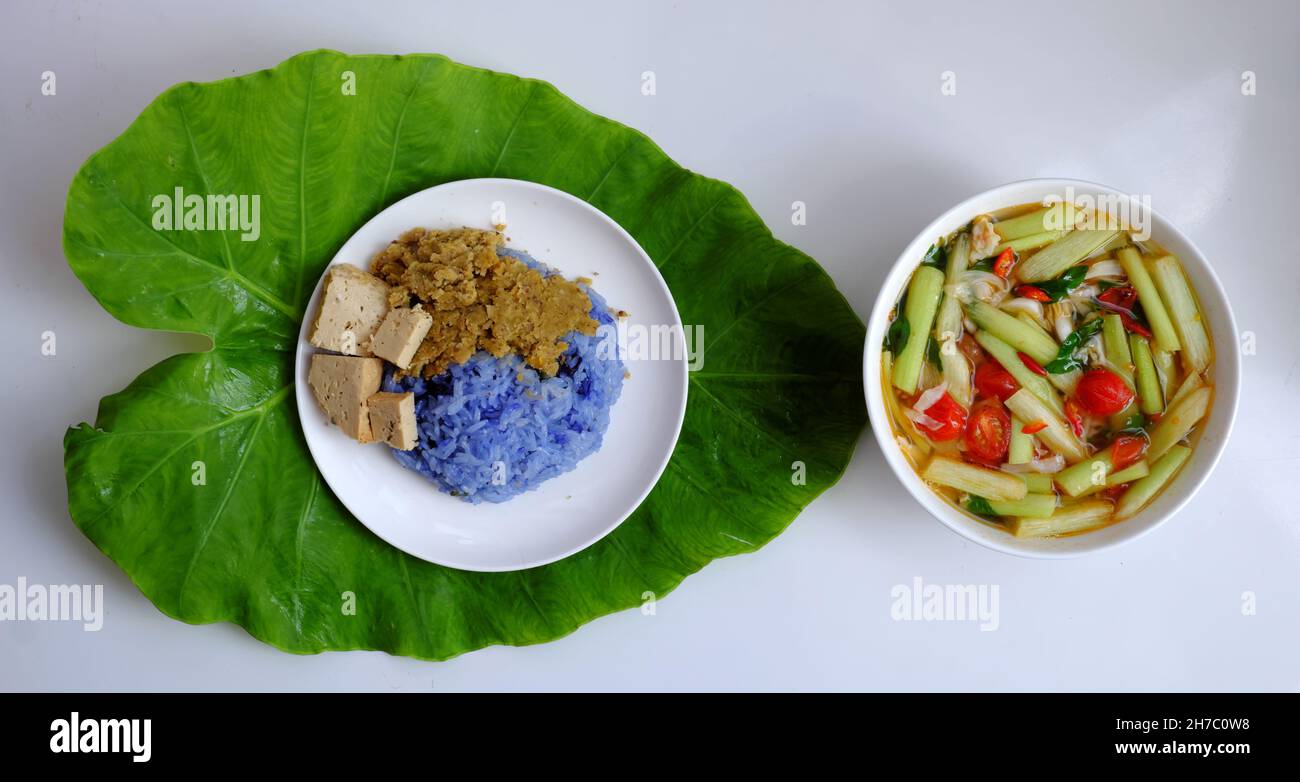 Vista dall'alto cibo vegano vietnamita per pranzo pasto, zuppa di pomodoro ciotola cuoco con maturo tamarindo, colocasia gigantea e foglia di basilico, piatto semplice ma delizioso Foto Stock