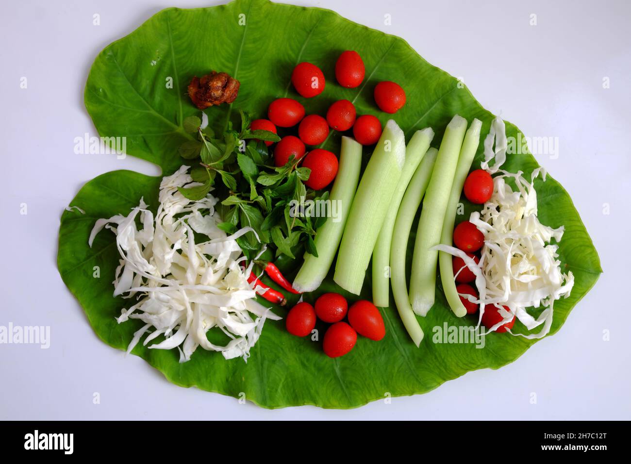 Vista dall'alto cibo vegano vietnamita per pranzo pasto, zuppa di pomodoro ciotola cuoco con maturo tamarindo, colocasia gigantea e foglia di basilico, piatto semplice ma delizioso Foto Stock
