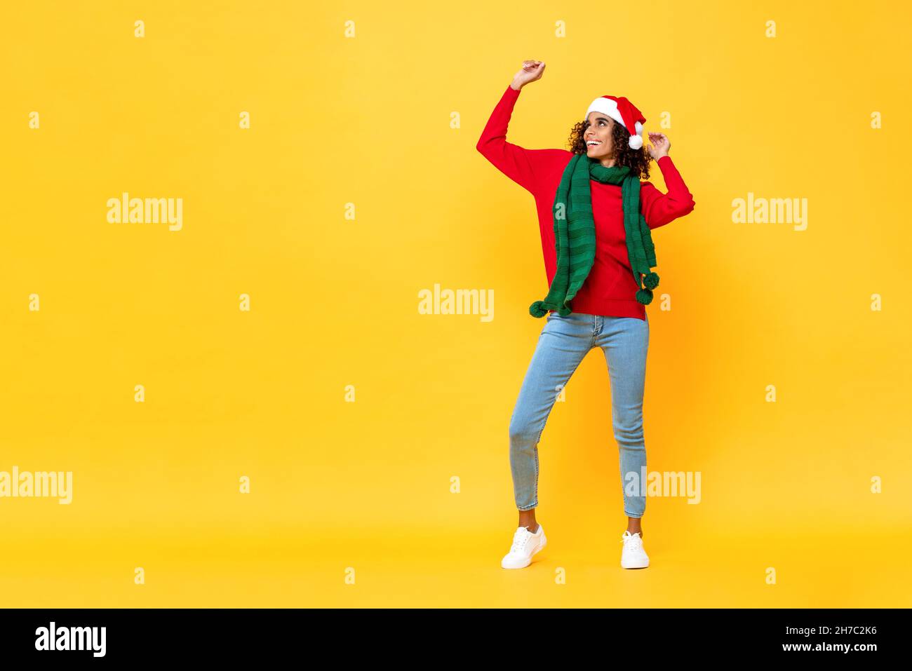 Ritratto a tutta lunghezza di divertimento felice Afircan donna americana in abbigliamento di Natale ballando su isolato sfondo giallo studio con spazio copia Foto Stock