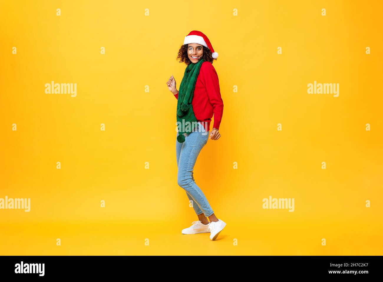 Eccitata donna felice in Natale in abbigliamento danzante in isolato sfondo giallo studio Foto Stock