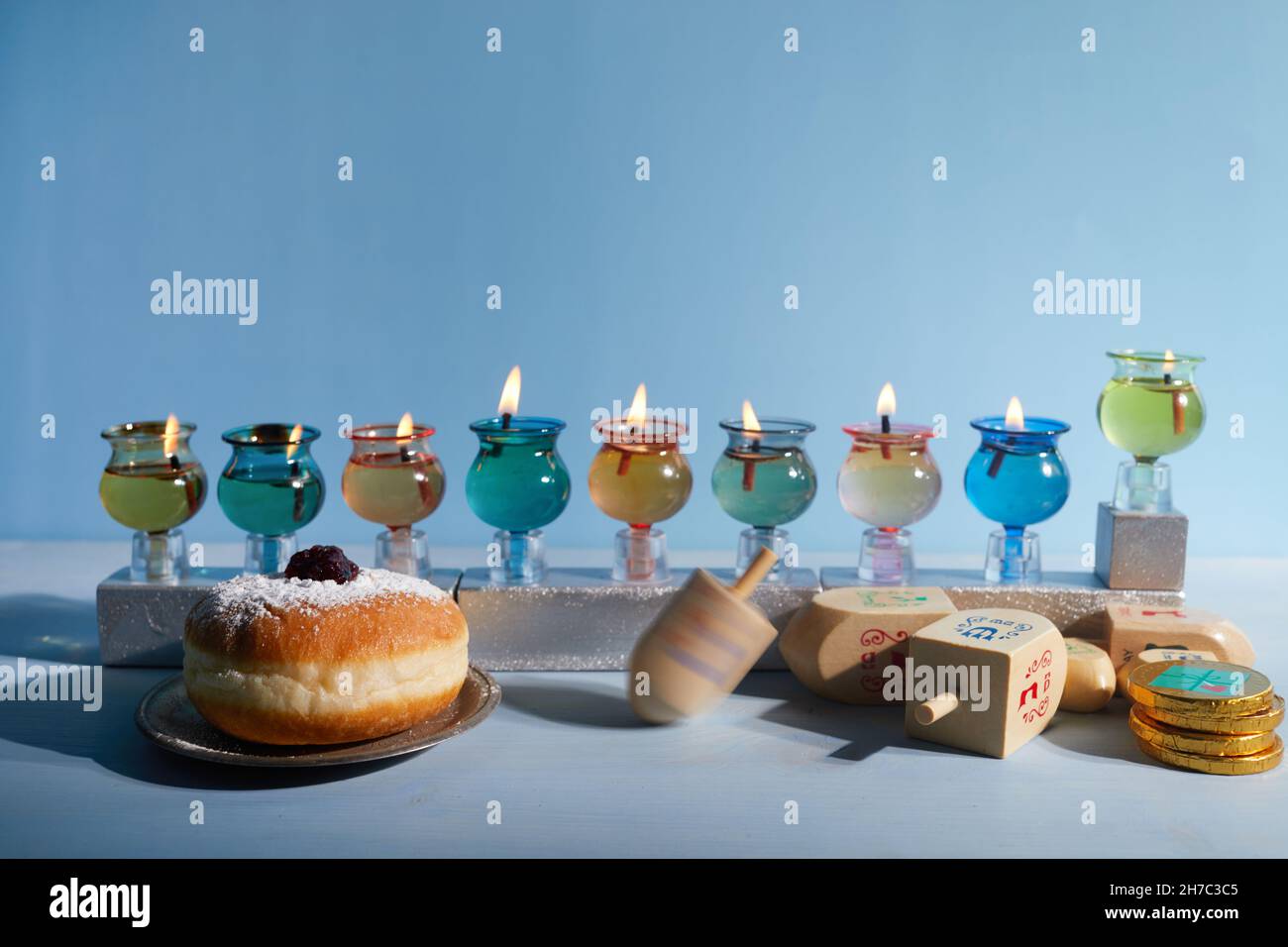 Vacanza ebraica Hanukkah sfondo con olio Menorah tradizionale candelabra, filatura top dreidil e Donut su sfondo blu Foto Stock