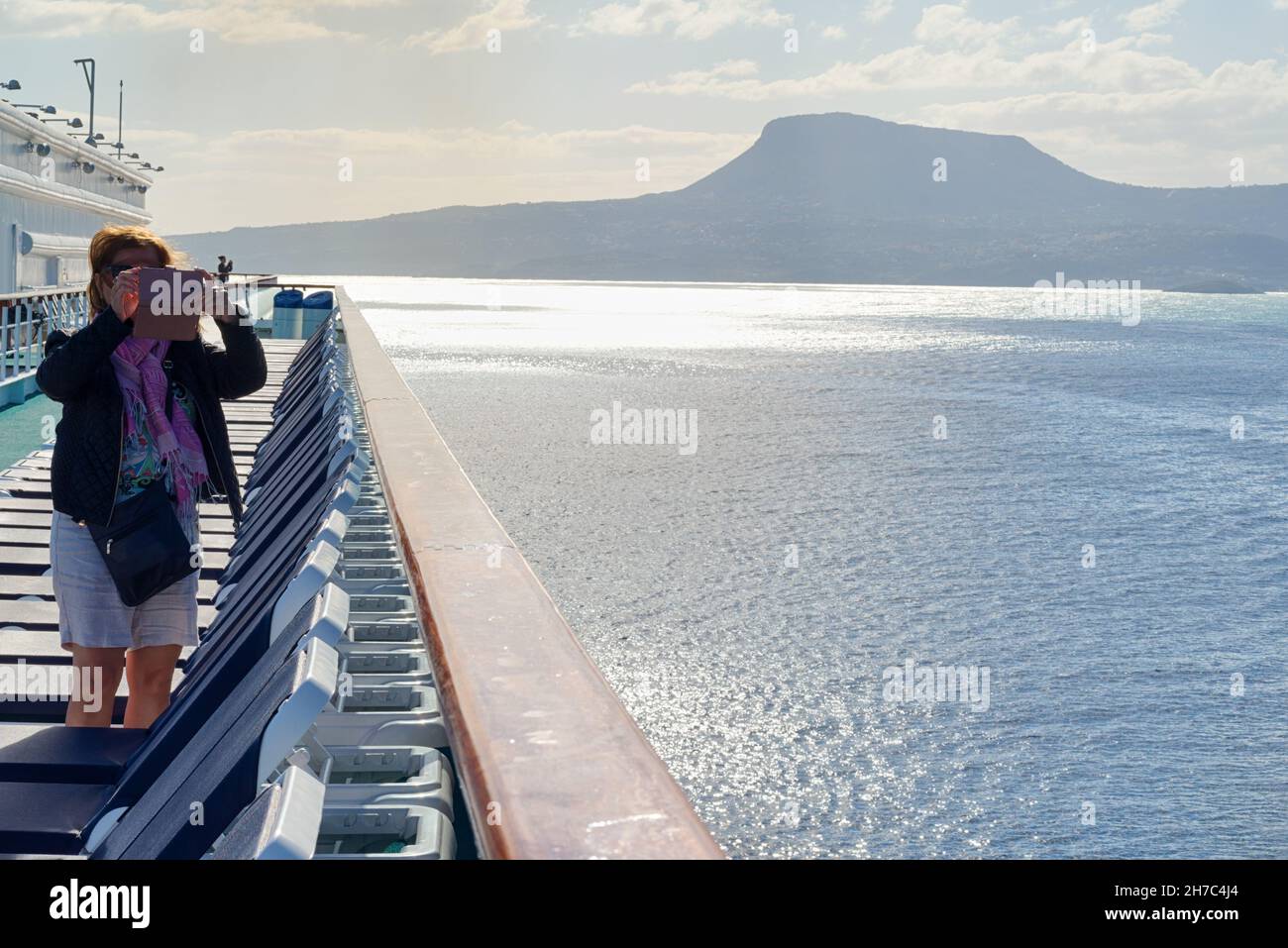 Donna in piedi su un ponte di nave fotografando con il suo cellulare Foto Stock