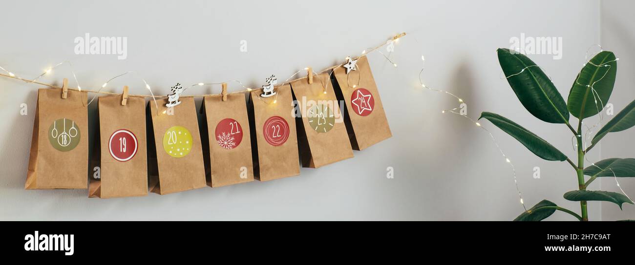 Calendario dell'avvento di Natale sospeso sul muro. Borse artigianali fatte a mano con regali e compiti per i bambini. Conto alla rovescia per la vigilia di Natale, in attesa del miracolo Foto Stock