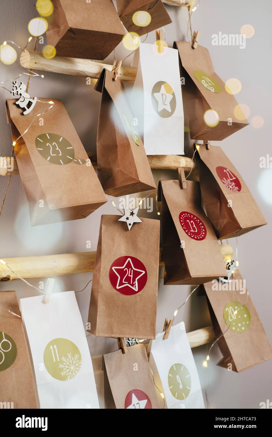 Calendario dell'avvento di Natale sospeso sul muro. Borse artigianali fatte a mano con regali e compiti per i bambini. Conto alla rovescia per la vigilia di Natale, in attesa del miracolo Foto Stock