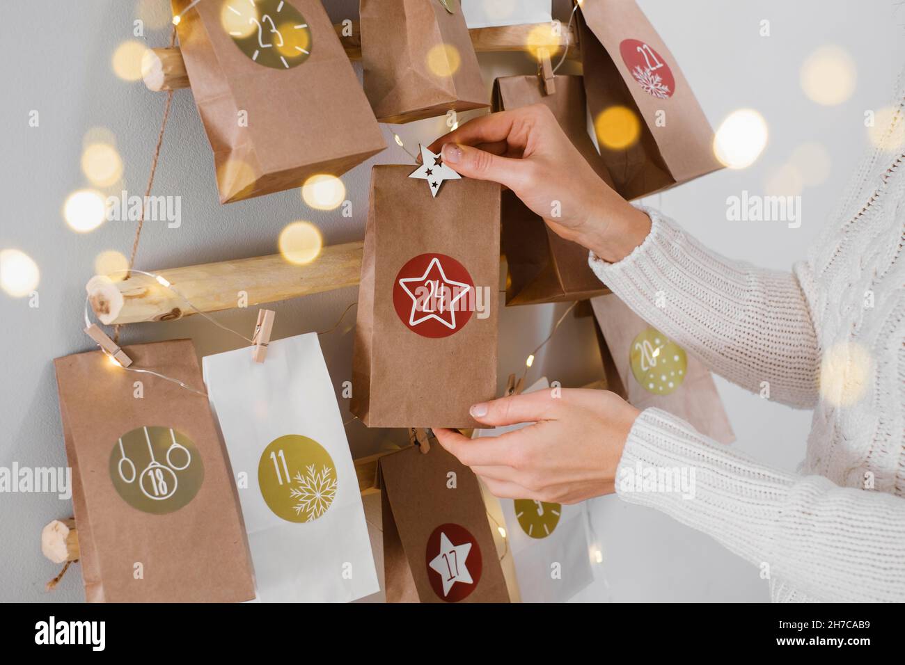 Calendario dell'avvento di Natale sospeso sul muro. Borse artigianali fatte a mano con regali e compiti per i bambini. Conto alla rovescia per la vigilia di Natale, in attesa del miracolo Foto Stock