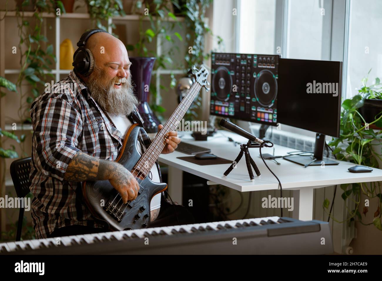 L'uomo obeso emozionale suona la chitarra elettrica nello studio di home audio Foto Stock