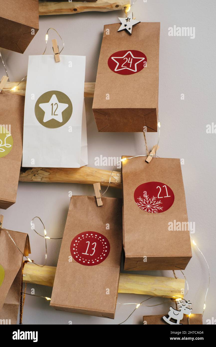 Calendario dell'avvento di Natale sospeso sul muro. Borse artigianali fatte a mano con regali e compiti per i bambini. Conto alla rovescia per la vigilia di Natale, in attesa del miracolo Foto Stock