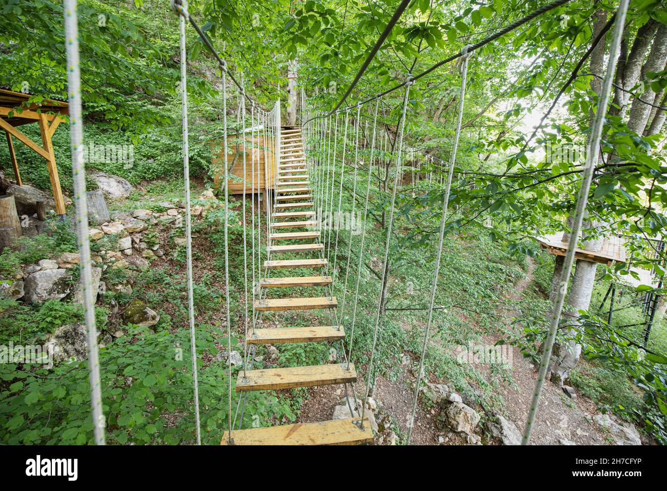 Un ponte sospeso con una scala in un parco funi come concetto di avventura e attività Foto Stock