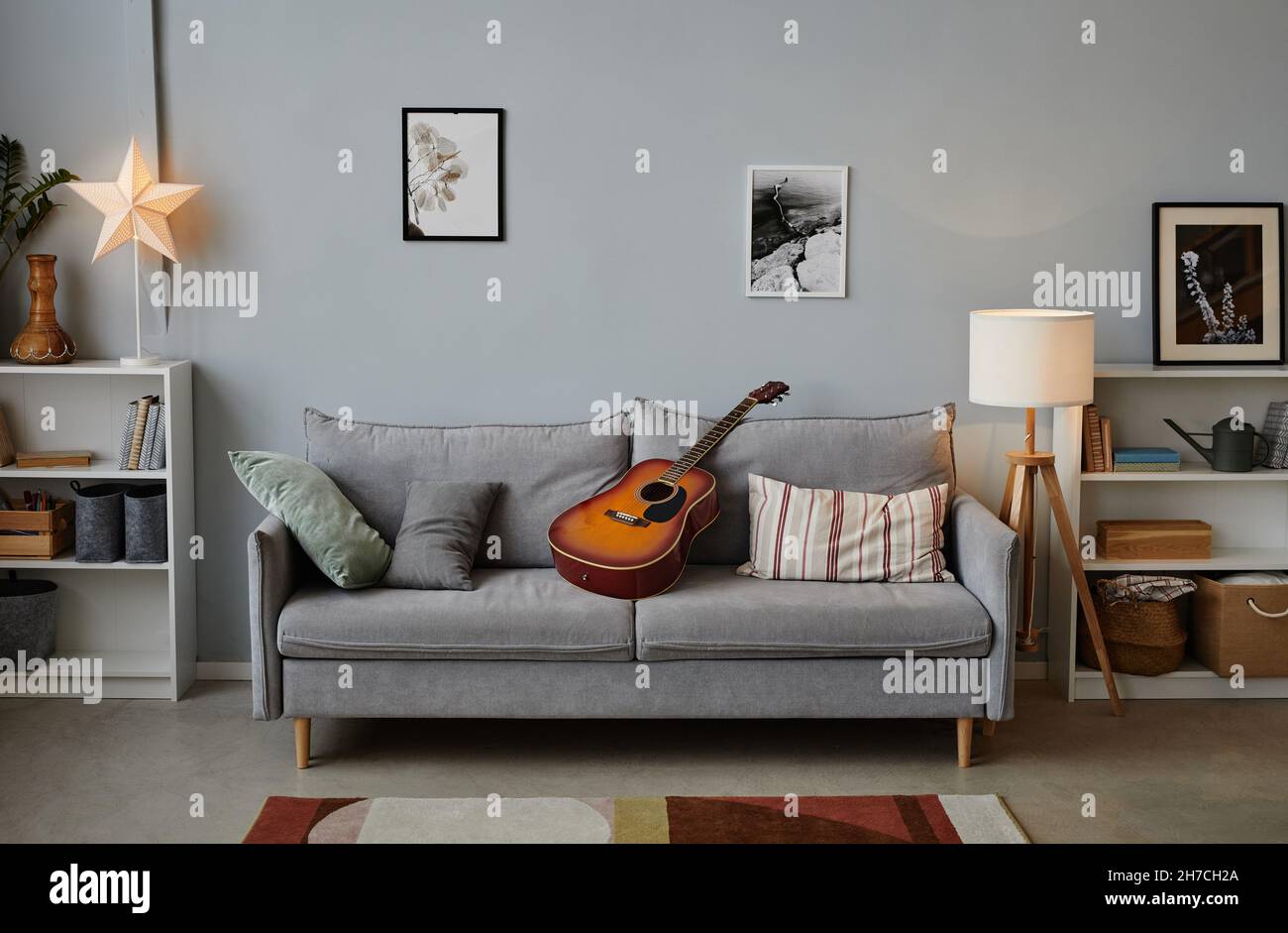 Immagine di sfondo della stanza dei ragazzi adolescenti con chitarra acustica su un comodo divano blu, spazio copia Foto Stock