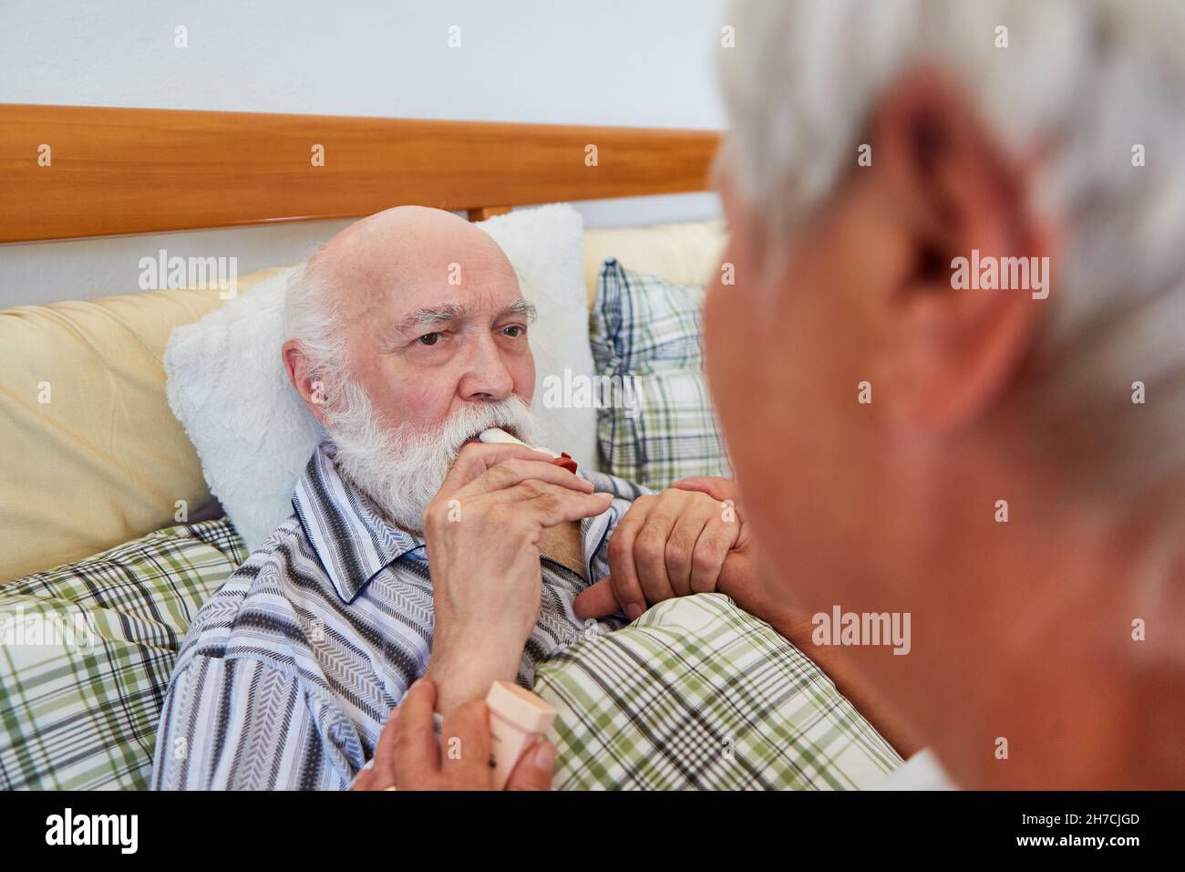 L'infermiere geriatrico aiuta gli anziani a letto con l'inalazione di cortisone spray contro le malattie respiratorie Foto Stock
