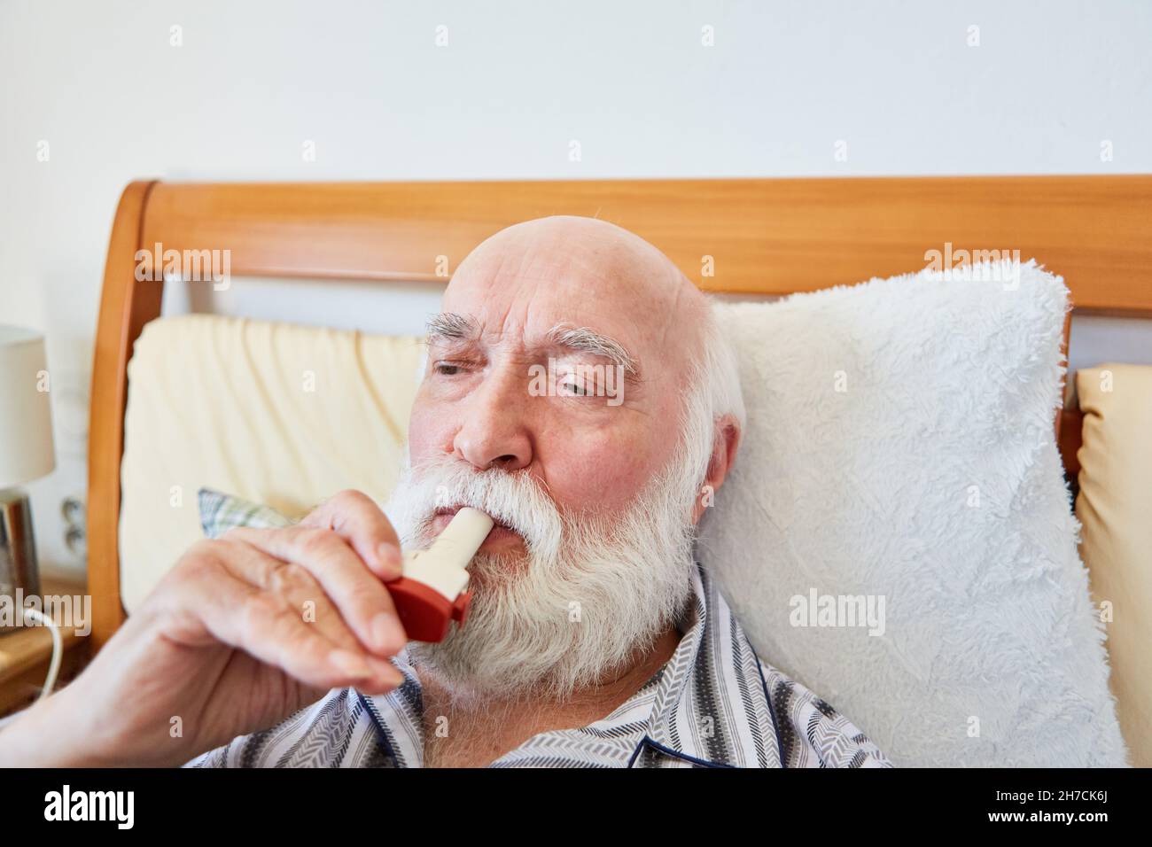 Senior a letto con malattia respiratoria cronica usa aerosol con asma spray Foto Stock
