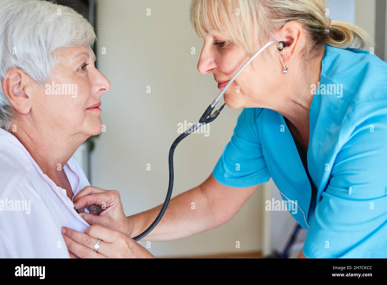 Medico generico con stetoscopio che ascolta il cuore e i polmoni di un paziente anziano Foto Stock