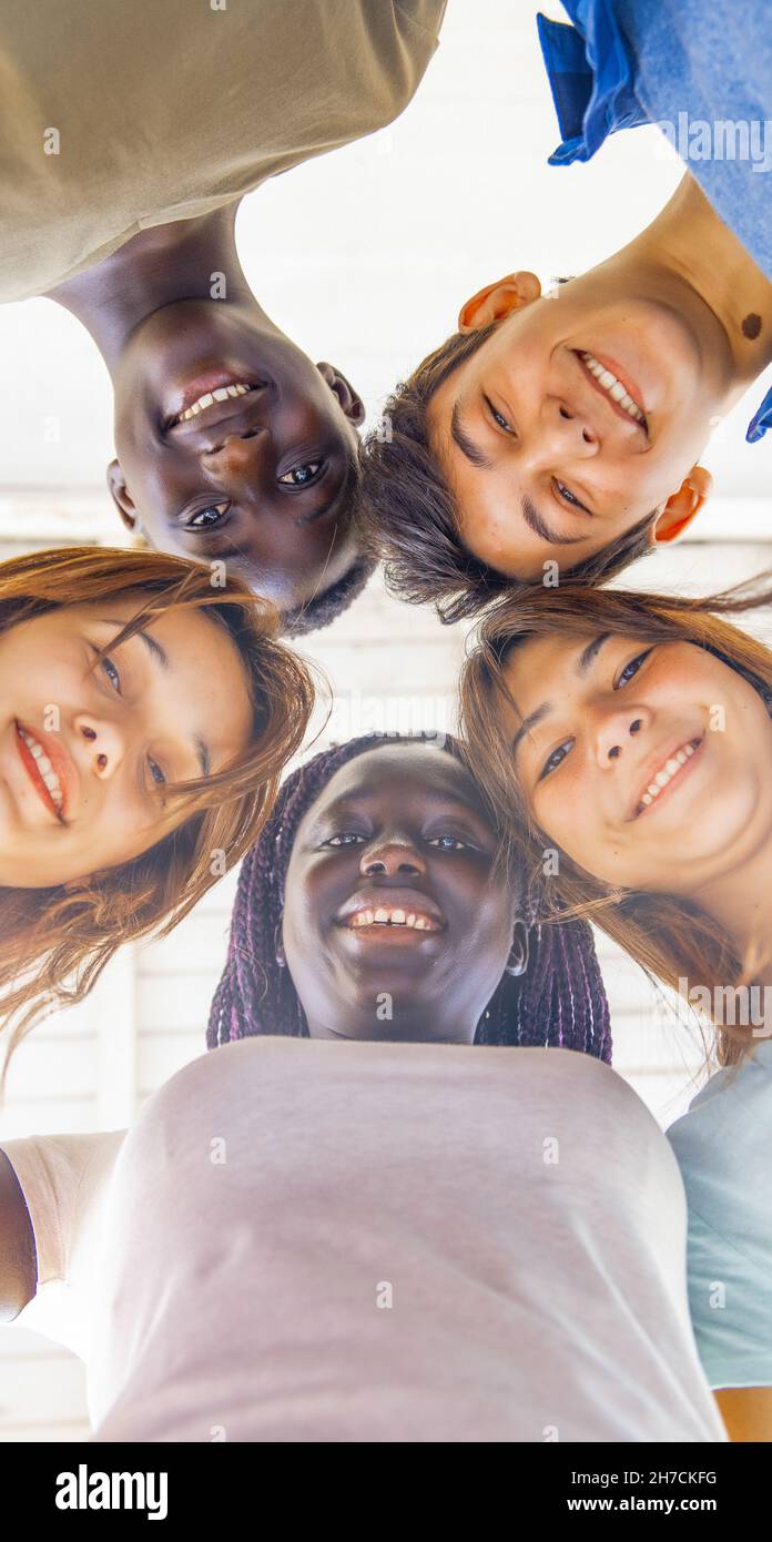Vista verso l'alto di adolescenti sorridenti insieme in un cerchio. Amici multietnici felice, libertà e antirazzismo concetto. Foto Stock
