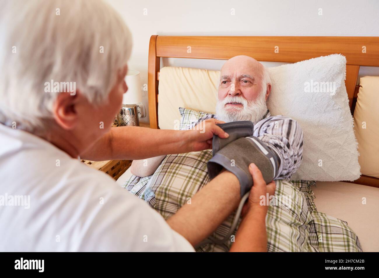 La donna che allatta aiuta il senior inhale asma spray a letto a casa Foto Stock