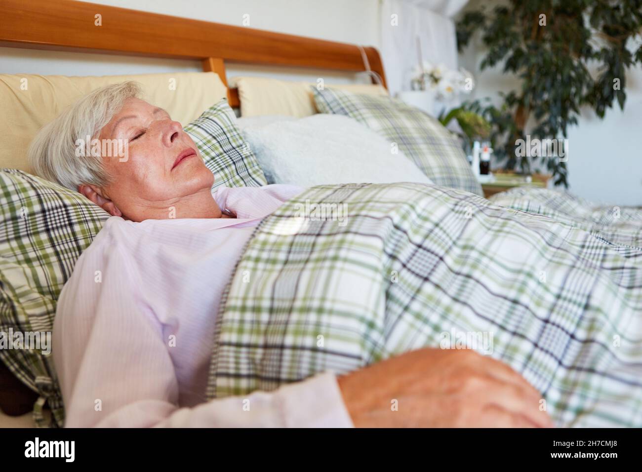 Anziani come paziente a letto con un pisolino pomeridiano a casa o in una casa di riposo Foto Stock