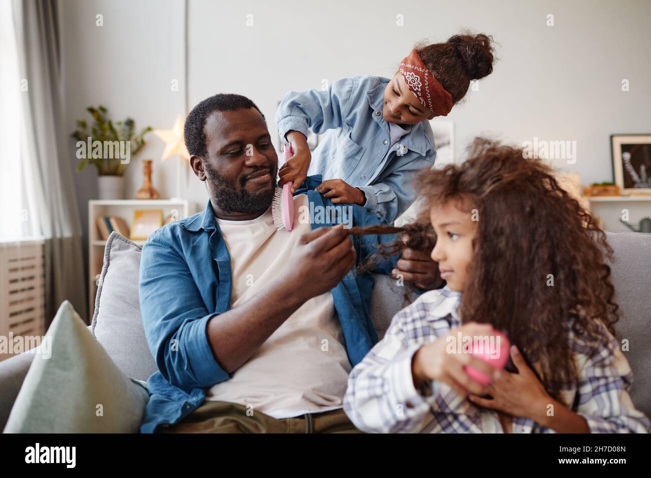 Ritratto di singolo padre afroamericano spazzolando i capelli di due figlie a casa, spazio copia Foto Stock