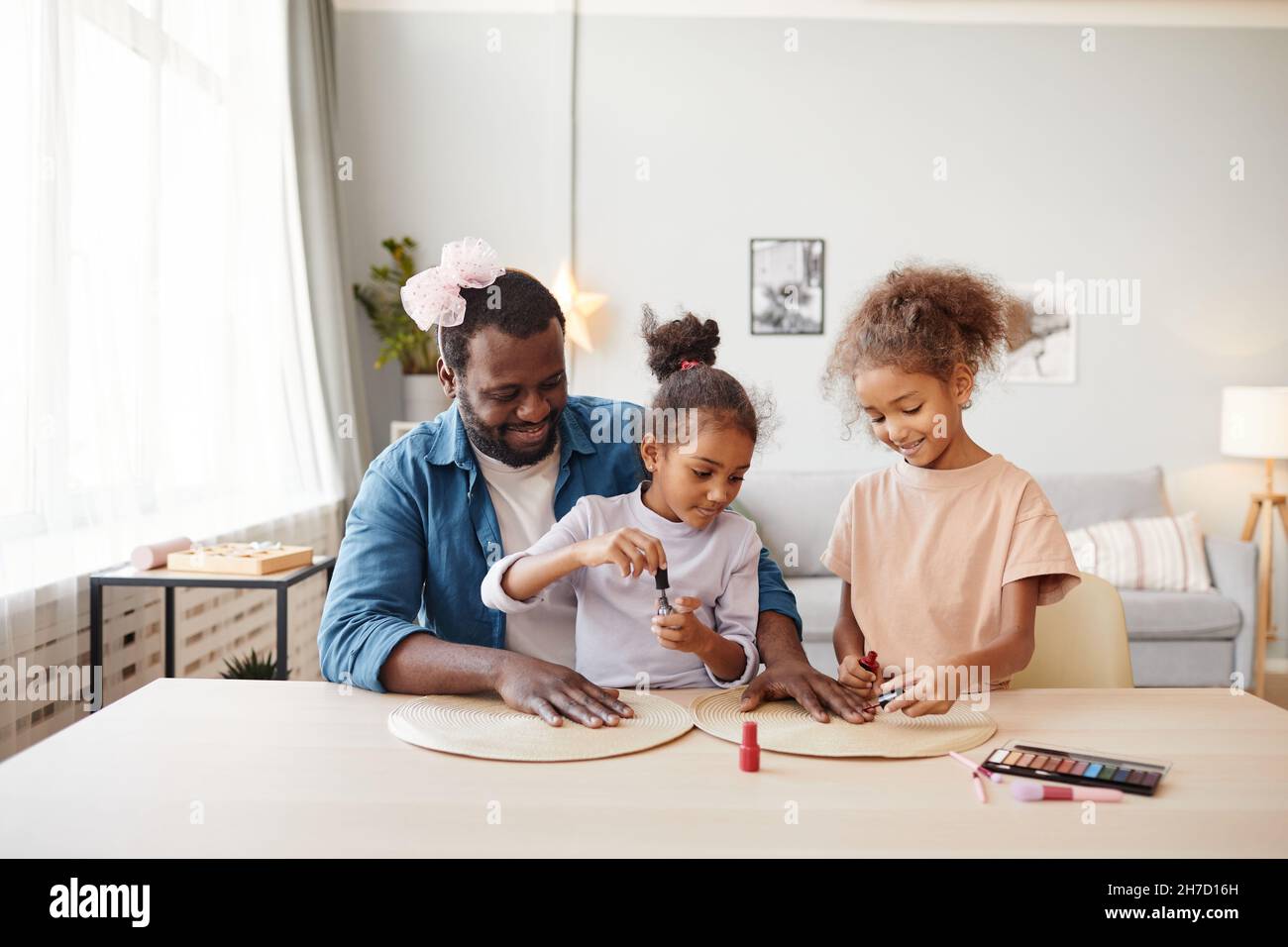 Ritratto di singolo padre afroamericano che gioca con due figlie e fare trucco, spazio copia Foto Stock