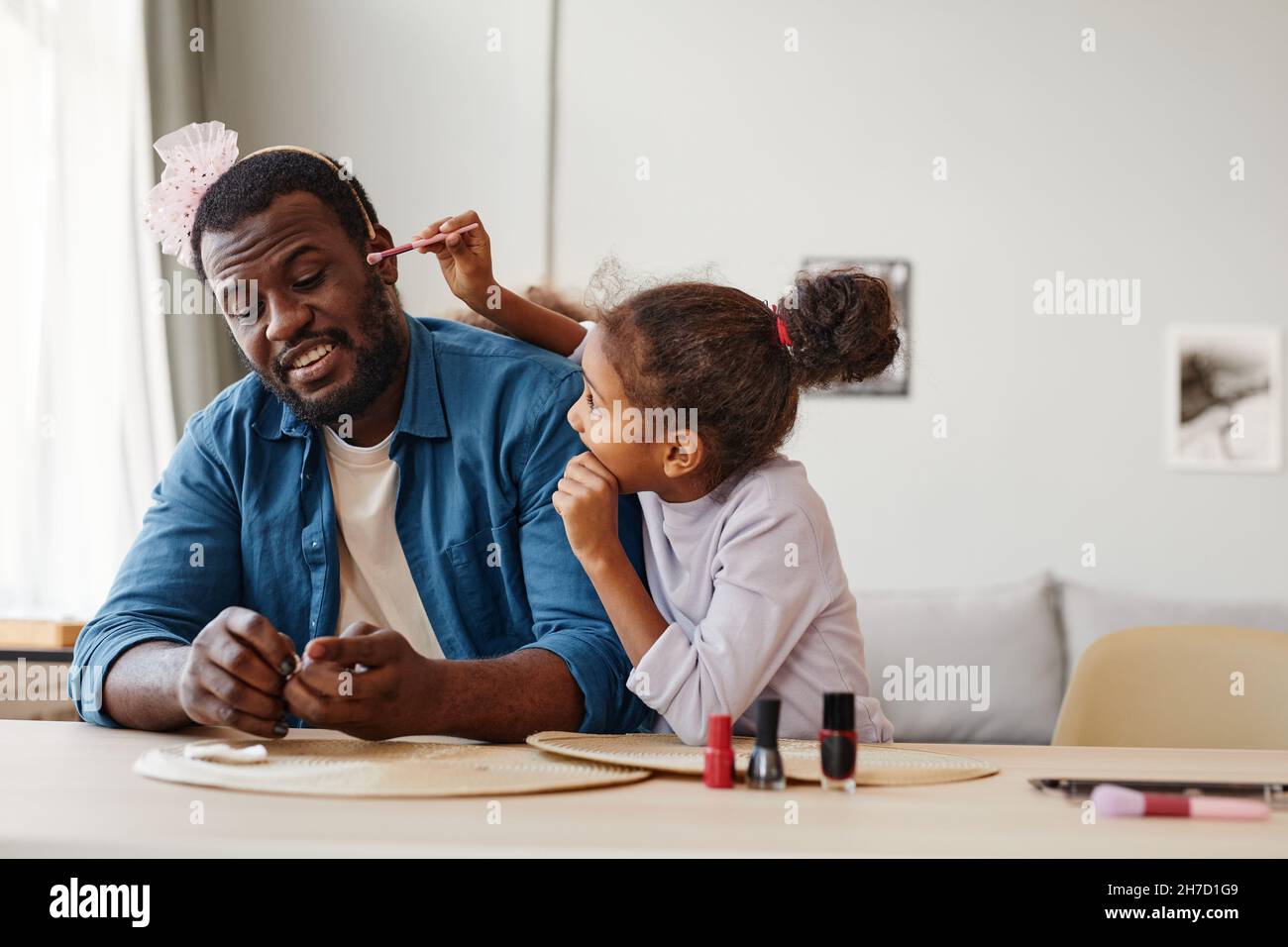 Ritratto di singolo padre afroamericano che gioca con la figlia a casa e fare il trucco, spazio copia Foto Stock