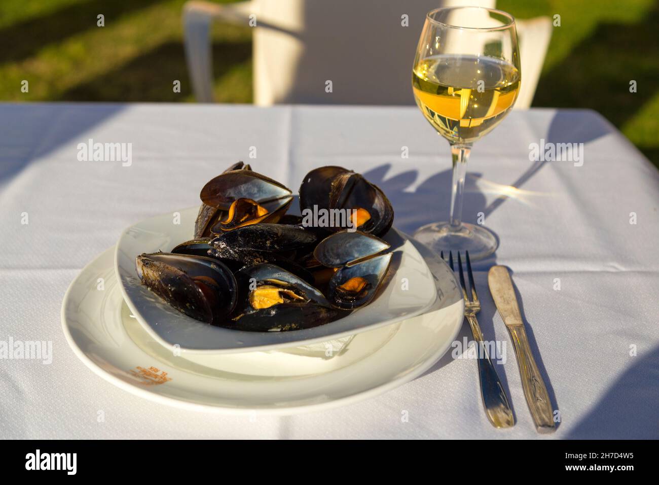 Tapas spagnole, cozze cotte in vino bianco, su tovaglia bianca all'aperto. Foto Stock
