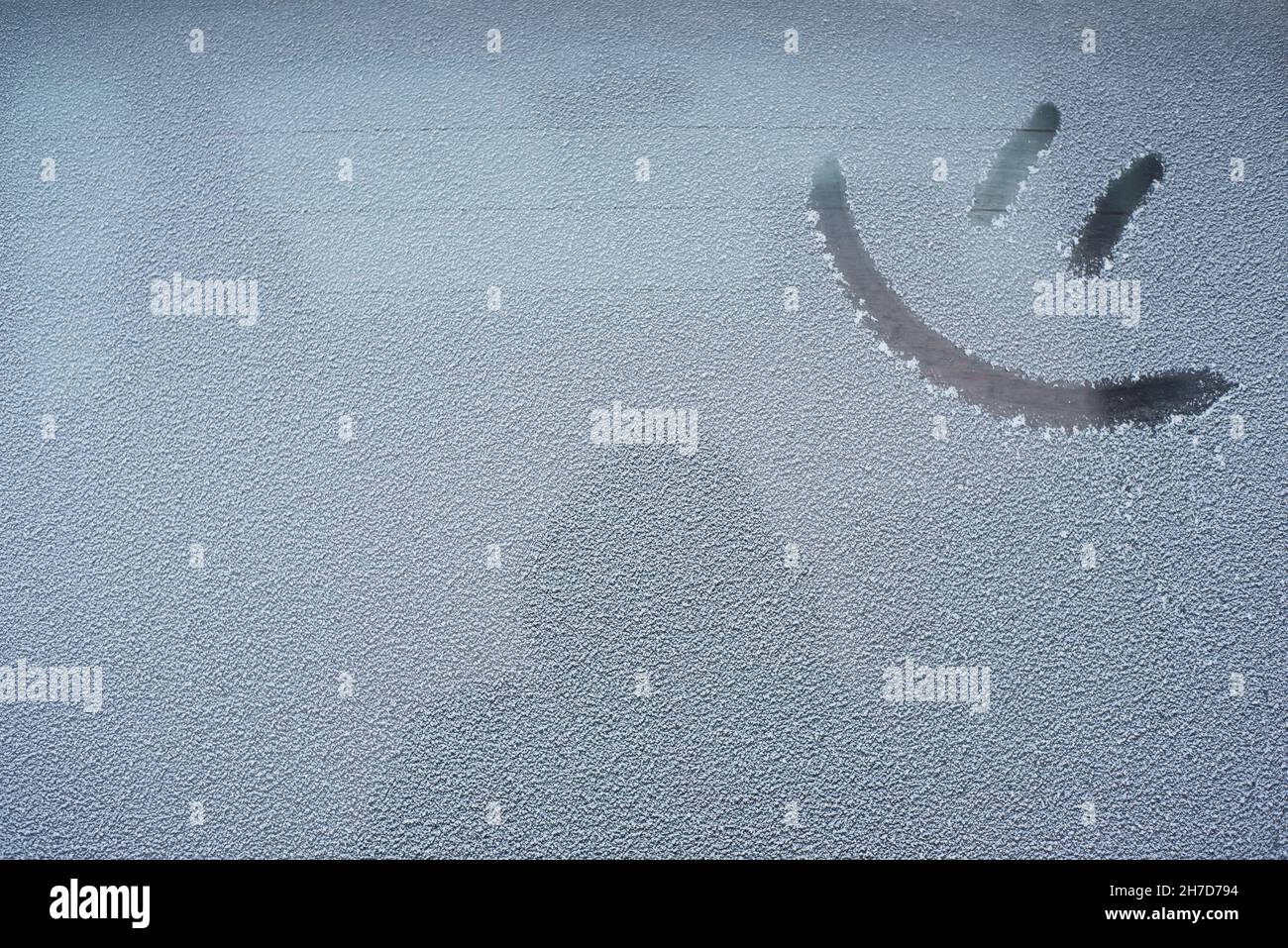 Un'emoticon da disegno su un finestrino innevato Foto Stock