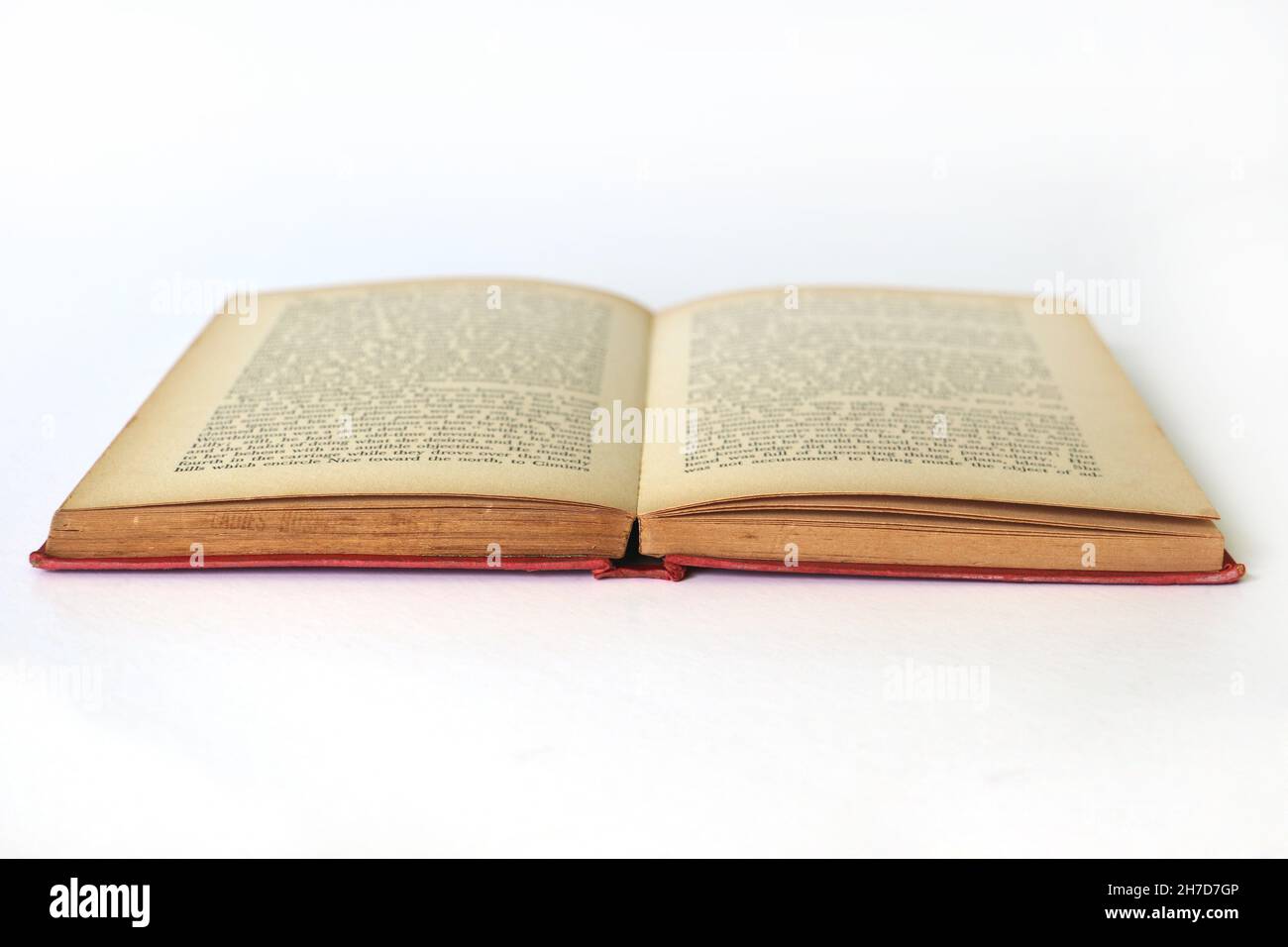 Vecchio libro aperto isolato con testo sfocato sulle pagine in difficoltà, girato da un angolo basso Foto Stock