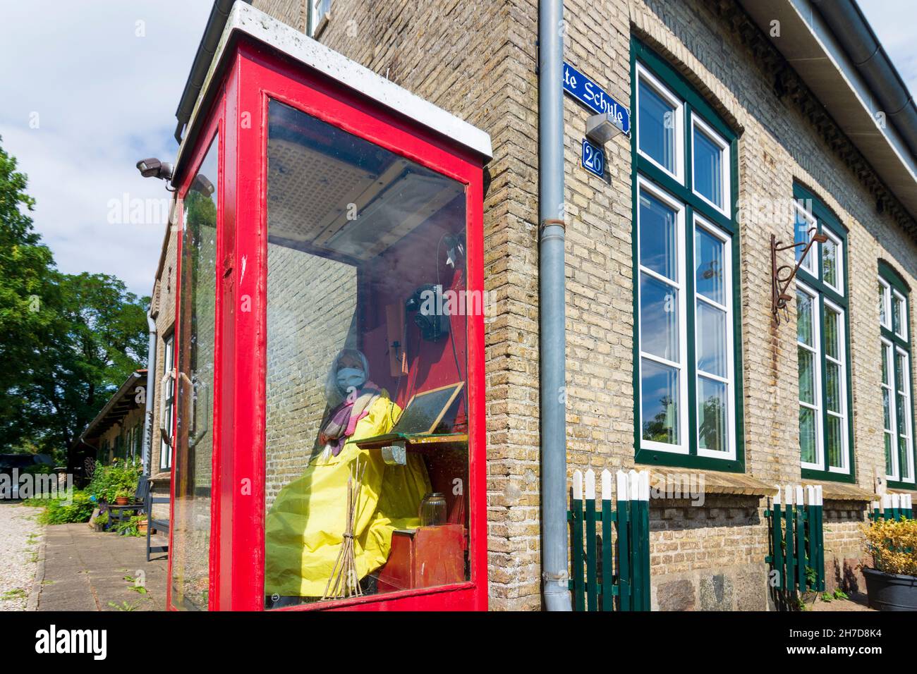 Idstedt: Ragazza d'arte con maschera di protezione del naso mout nella vecchia cabina telefonica al ristorante 'Alte Schule' a Binnenland, Schleswig-Holstein, Germania Foto Stock