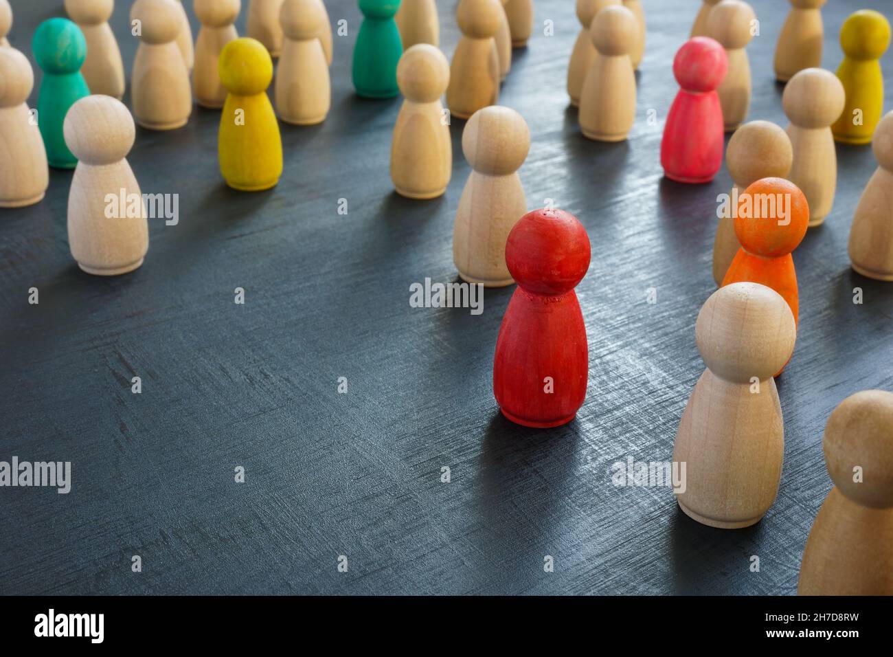 Figurine colorate tra quelle in legno. Inclusività e unicità. Foto Stock