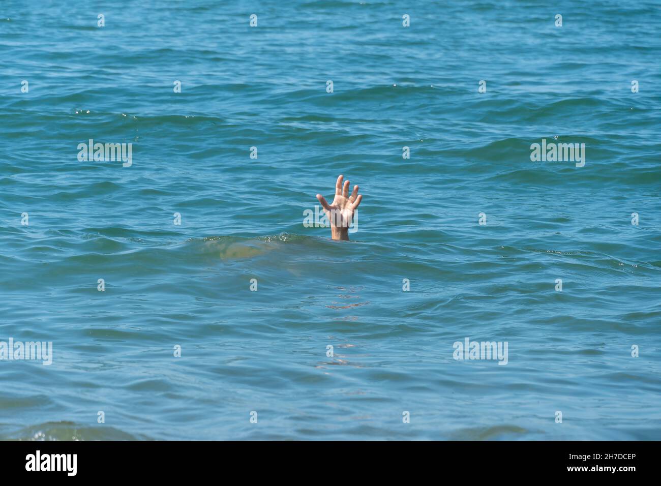 Una mano di un uomo annegante in mare, chiedendo aiuto in una giornata di sole Foto Stock