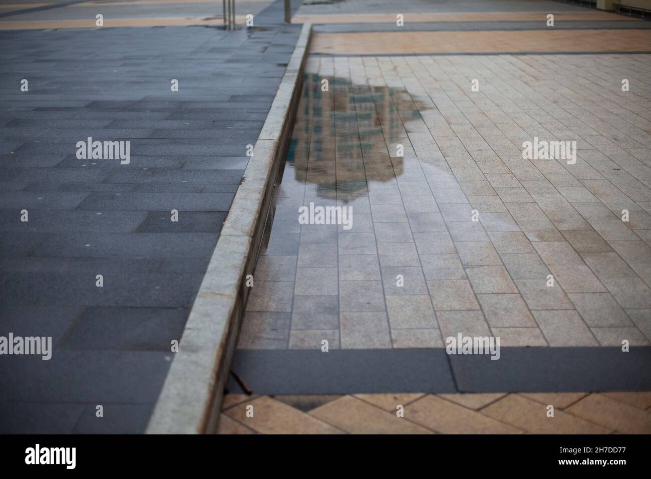 Pozzanghere sulla zona pedonale. La strada dopo la pioggia. Dettagli della città in cattive condizioni meteorologiche. Foto Stock