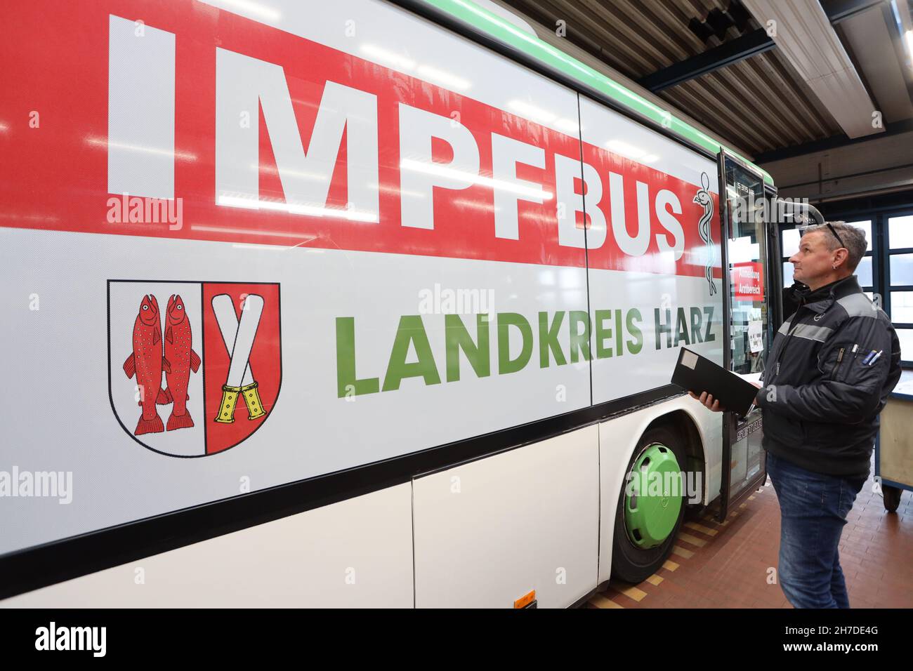 Wernigerode, Germania. 22 novembre 2021. I dipendenti di una società pubblicitaria contrassegnano un autobus della Harzer Verkehrsbetriebe HVB, che è stato convertito in un autobus di vaccinazione, in un laboratorio del deposito. Per accelerare ulteriormente la campagna di vaccinazione, giovedì prossimo il distretto di Harz metterà in funzione un autobus per la vaccinazione, al fine di fornire anche alle piccole città del distretto di Harz offerte di vaccinazione. Credit: dpa/dpa-Zentralbild/dpa/Alamy Live News Foto Stock