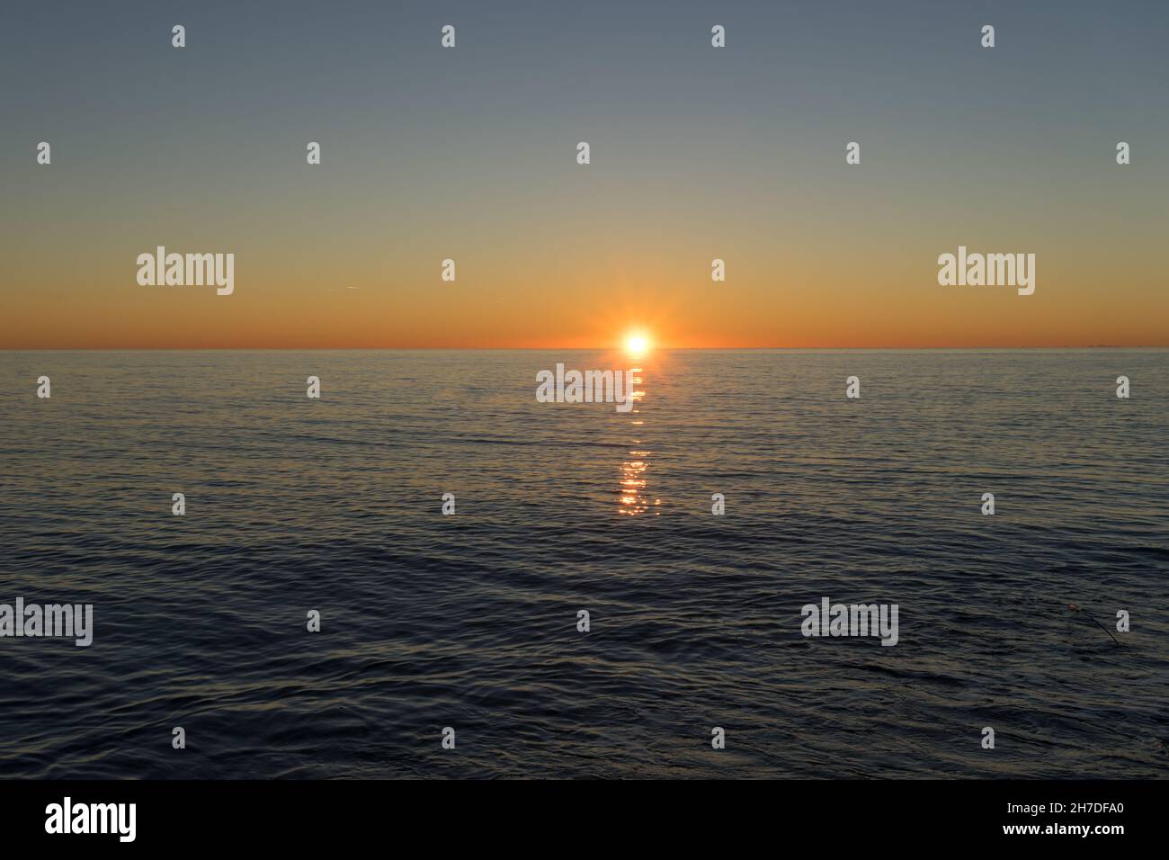 Seascape con un bel tramonto oltre l'orizzonte e la superficie dell'acqua. Foto Stock