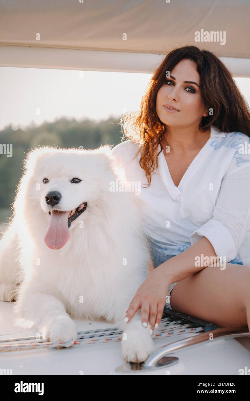 una donna felice con un grande cane bianco su uno yacht bianco in mare Foto Stock