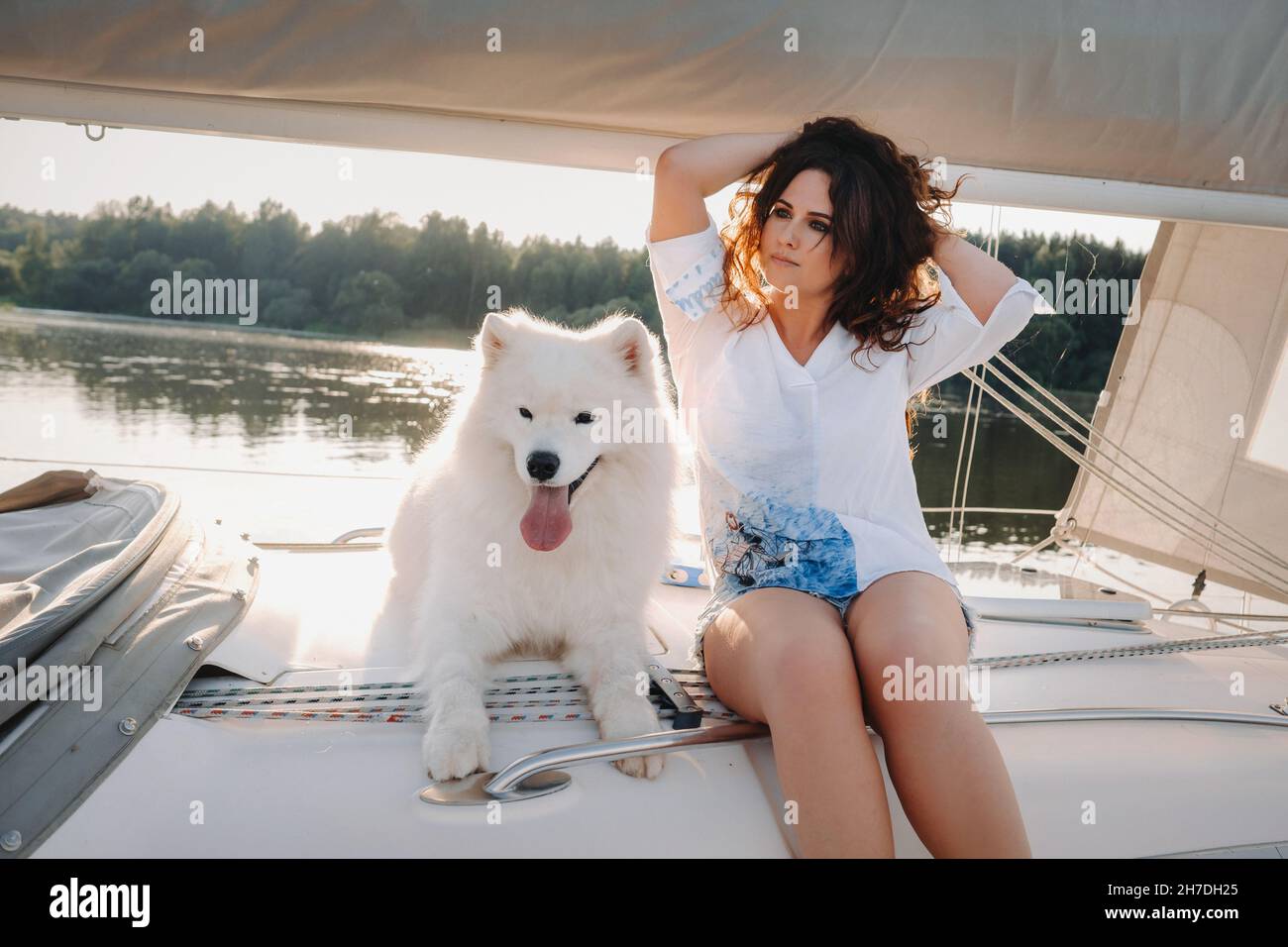 una donna felice con un grande cane bianco su uno yacht bianco in mare Foto Stock