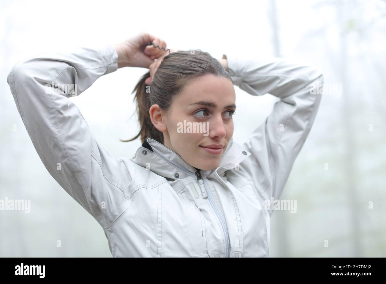 Felice escursionista fare ponytail in una foresta nebbia Foto Stock