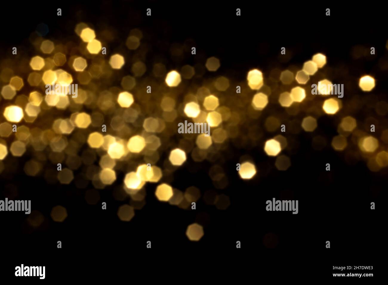 Il bokeh dorato sfocato si illumina su sfondo nero. Stelle scintillanti per festeggiare. Overlay per il tuo progetto Foto Stock