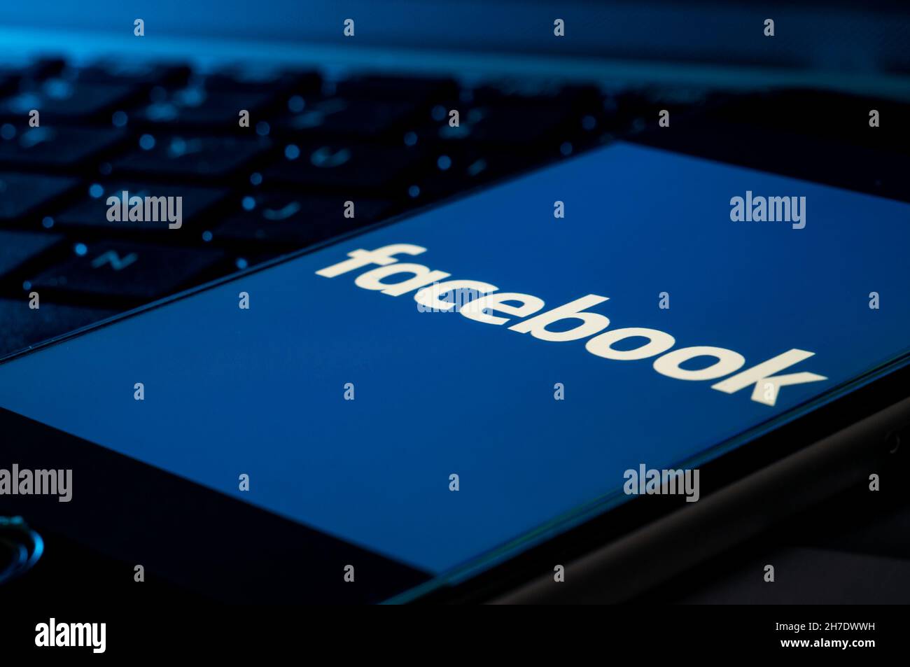 Smartphone su una tastiera del computer con il logo Facebook Foto Stock
