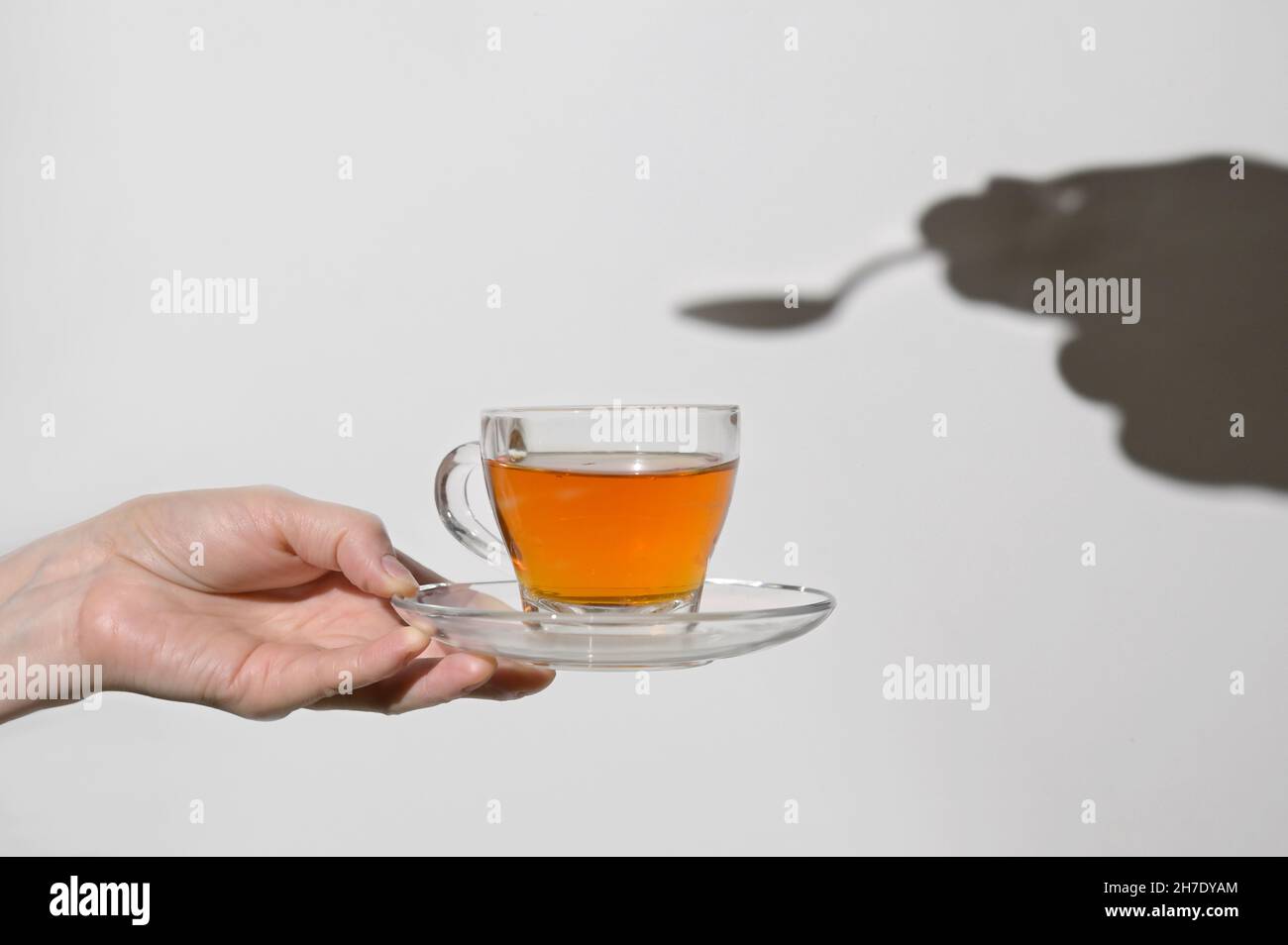 Coppa concettuale di tè e ombra di cucchiaio e mano Foto Stock