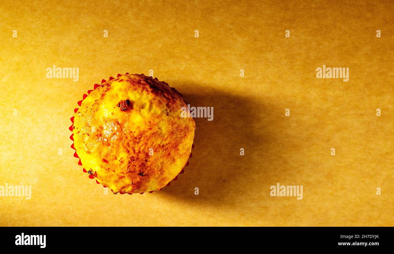 un cupcake viene girato con la luce laterale in studio su un vecchio sfondo di carta. Cucina a casa Foto Stock