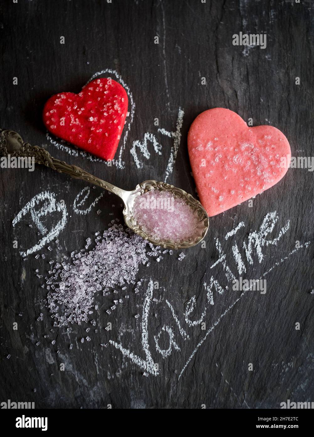Gesso scritta 'Be my Valentine' con biscotti di cuore e zucchero rosa Foto Stock
