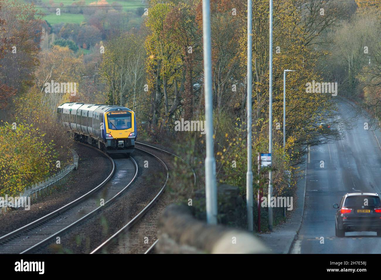 Un treno ferroviario del nord passa attraverso Calderdale accanto alla A58 strada principale di Leeds tra Halifax e Hipperholme nel West Yorkshire, Inghilterra, Regno Unito Foto Stock