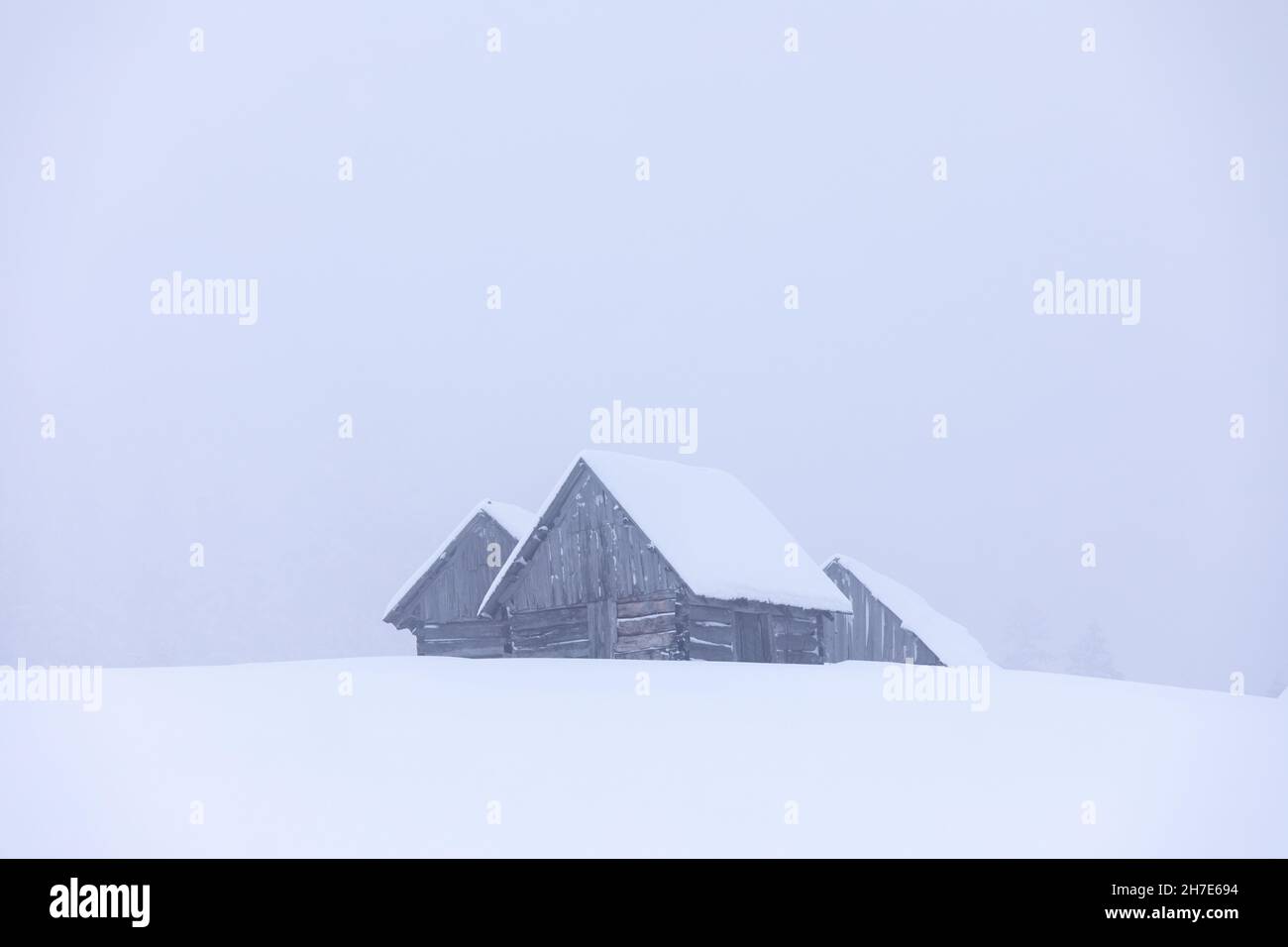 Paesaggio nei giorni invernali. Vecchia casa di legno del forester sul prato coperto di neve. Nevicate. Paese delle meraviglie di Natale. Alta montagna. Carta da parati innevata b Foto Stock