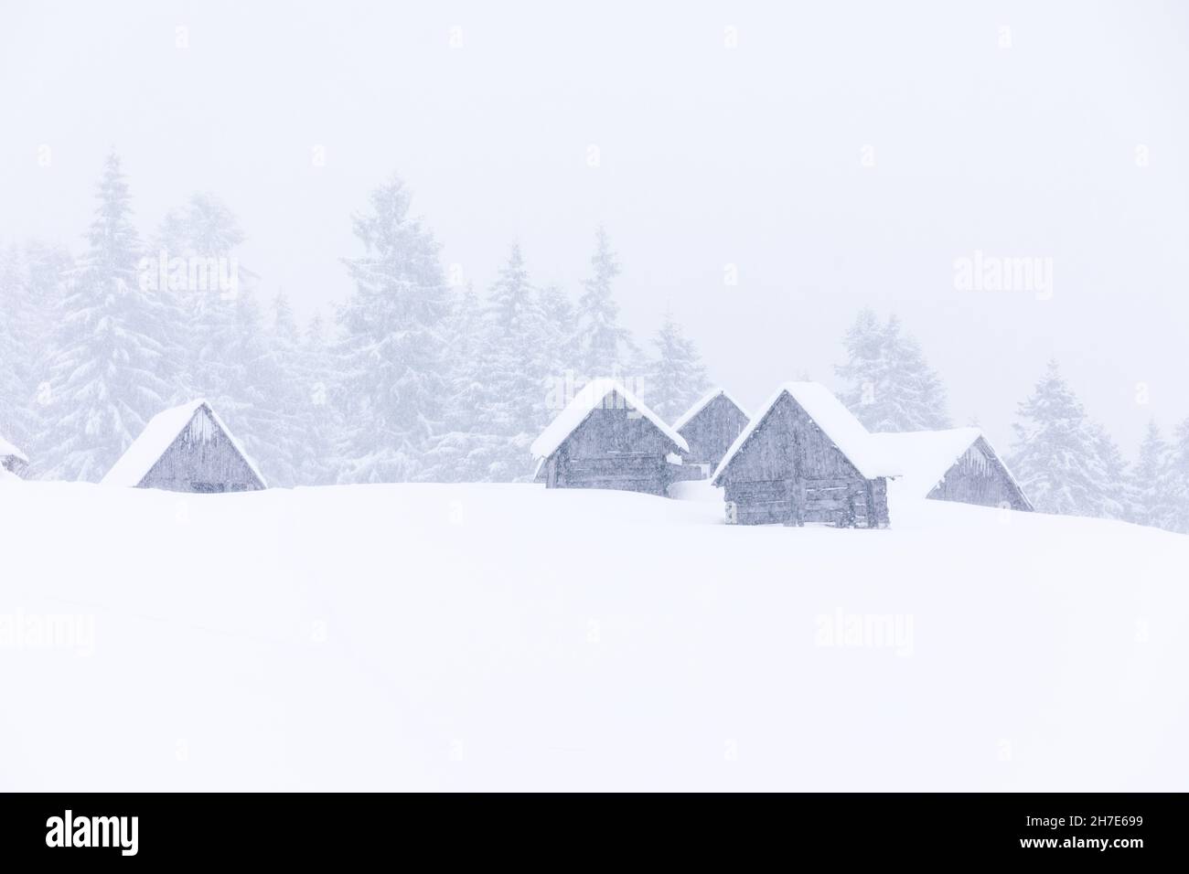 Vecchia casa di legno del forester sul prato coperto di neve. Paesaggio nei giorni invernali. Nevicate. Paese delle meraviglie di Natale. Alta montagna. Carta da parati innevata b Foto Stock