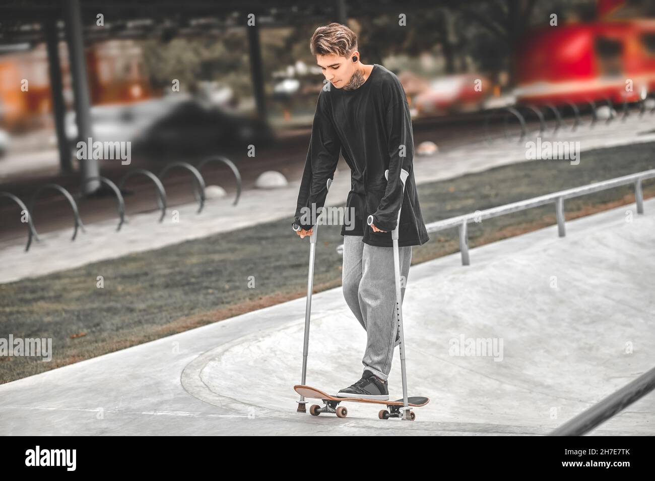 Tizio sulle stampelle sulla rampa di arrampicata per skateboard Foto Stock