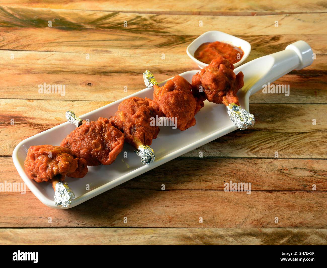 Il lecca di pollo è un antipasto indiano cinese servito su uno sfondo rustico in legno. Fuoco selettivo Foto Stock