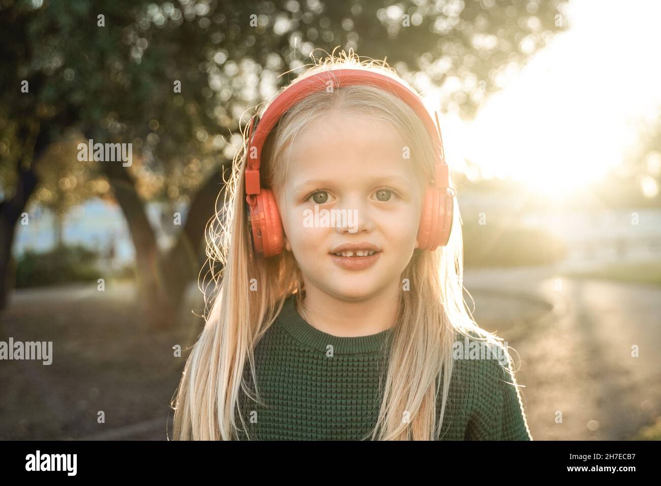 Buon ragazzino che ascolta la musica delle playlist con le cuffie all'aperto - Focus on Face Foto Stock