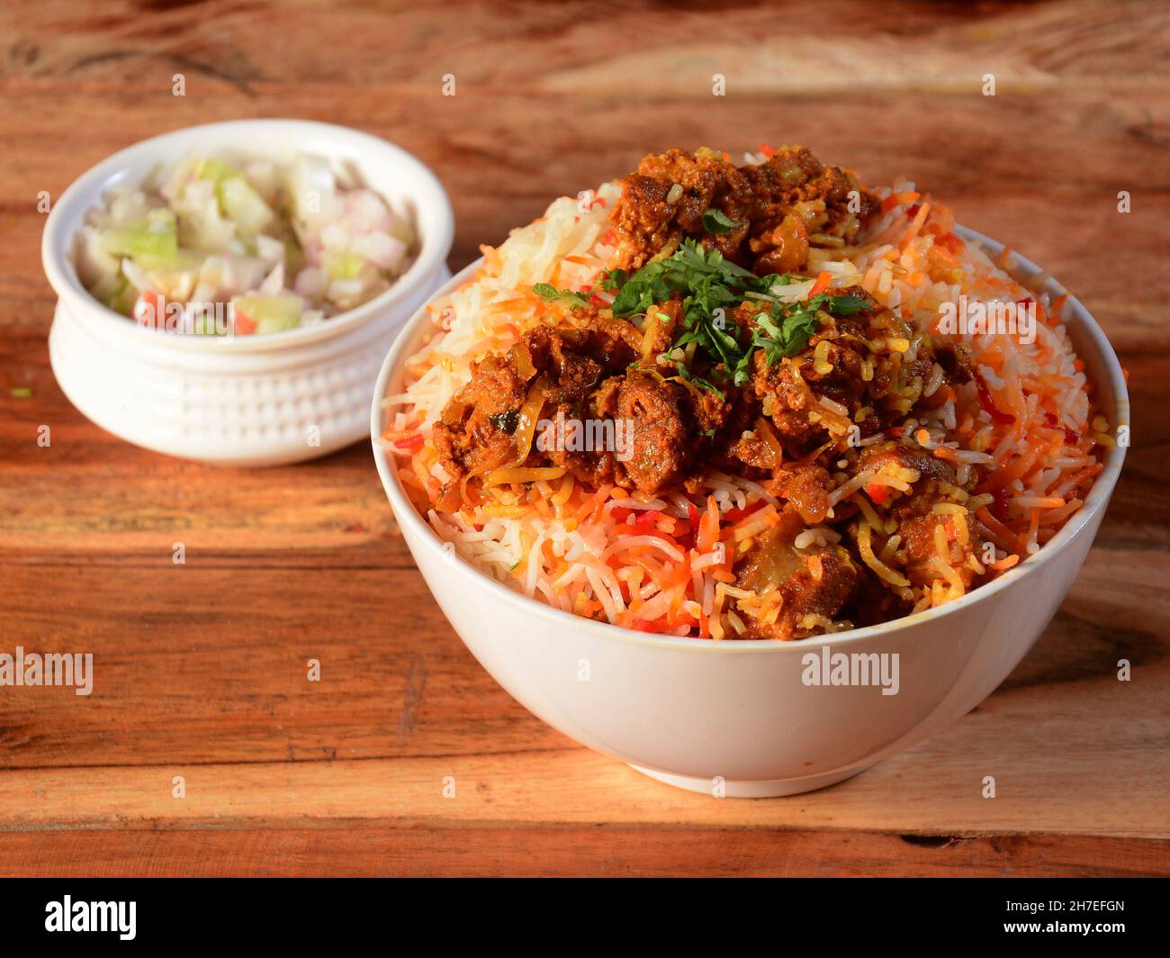 Kashmiri Mutton Gosht o Agnello Biryani preparato in riso Basmati servito con cipolla su sfondo rustico in legno, fuoco selettivo Foto Stock