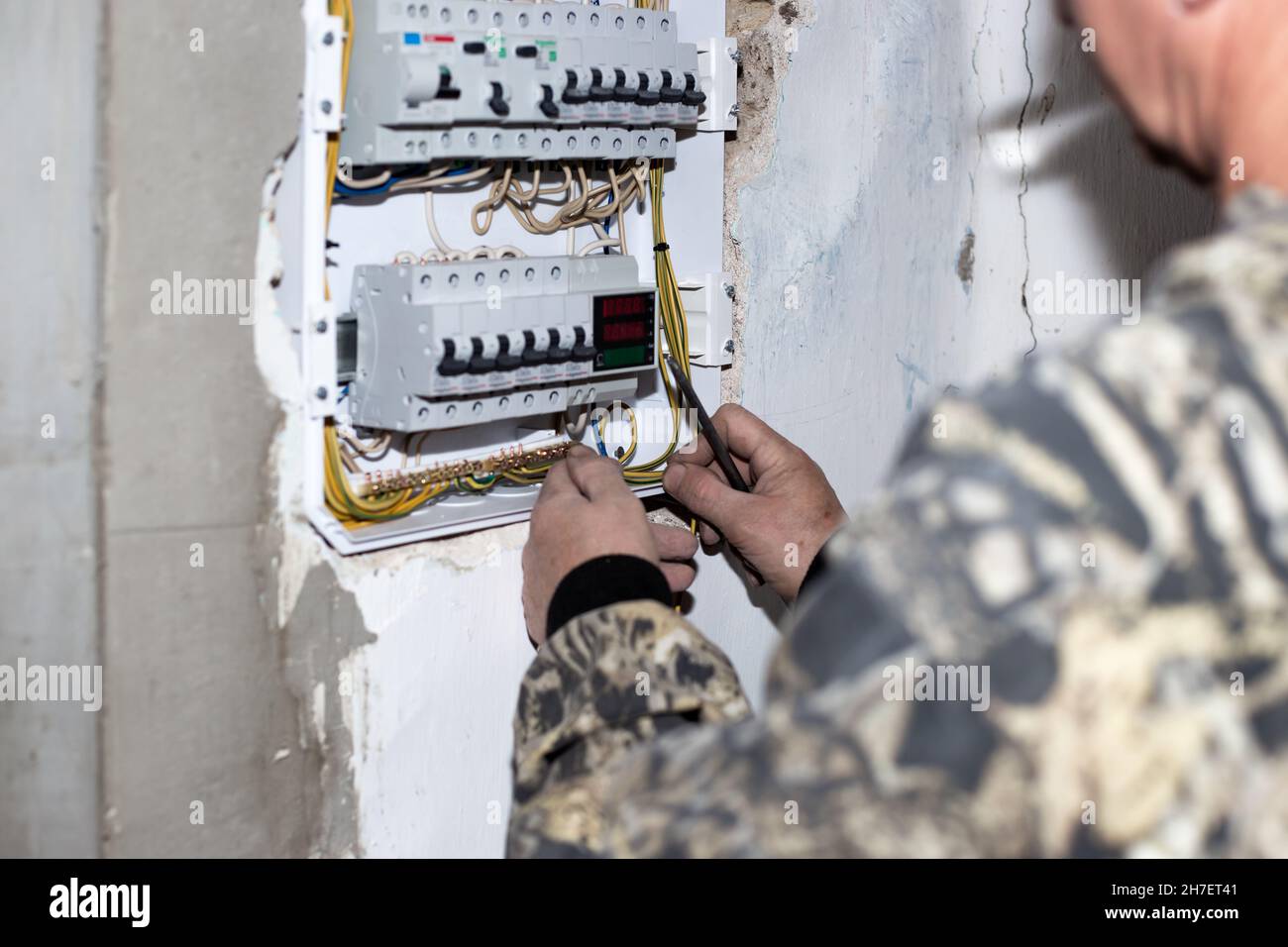 Un elettricista installa un quadro elettrico con interruttori a levetta per fornire elettricità alla casa. Foto Stock