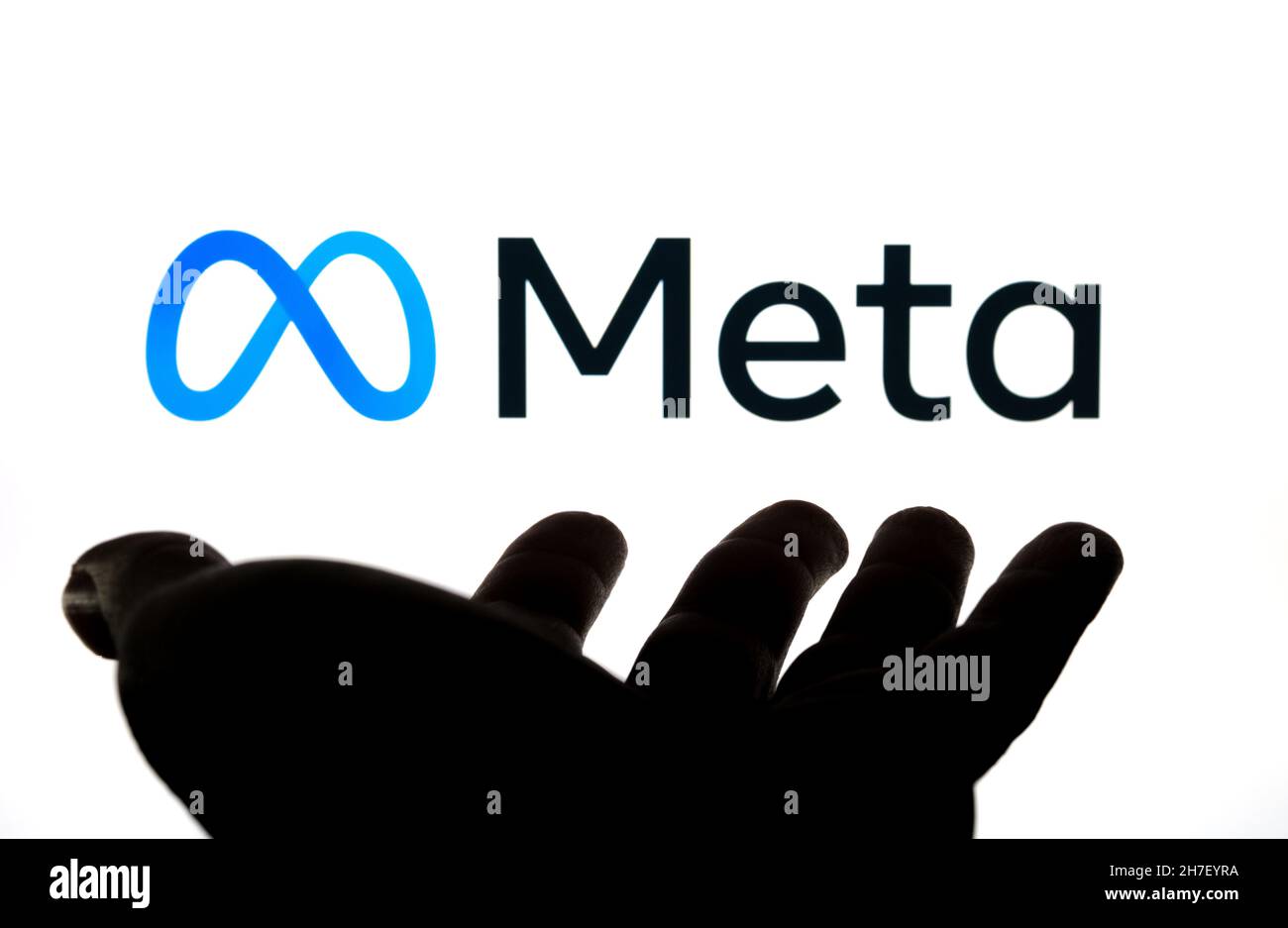 Facebook META Platforms logo aziendale visto su sfondo sfocato e silhuette di mano aperta di fronte ad esso. Concetto. Stafford, Regno Unito, N. Foto Stock