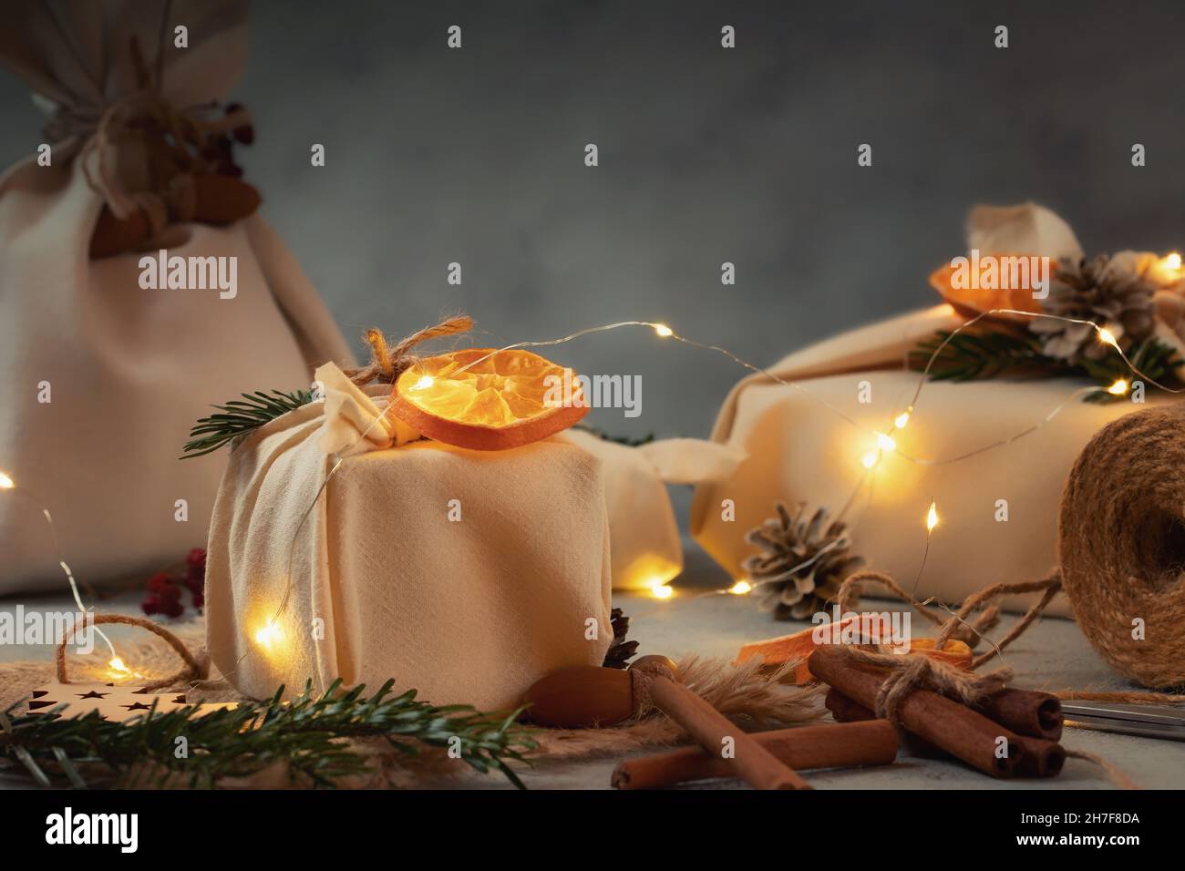 Zero spreco di natale concetto. Confezionato in tessuti naturali regali e decorazioni in materiali naturali con luci di natale. Foto Stock