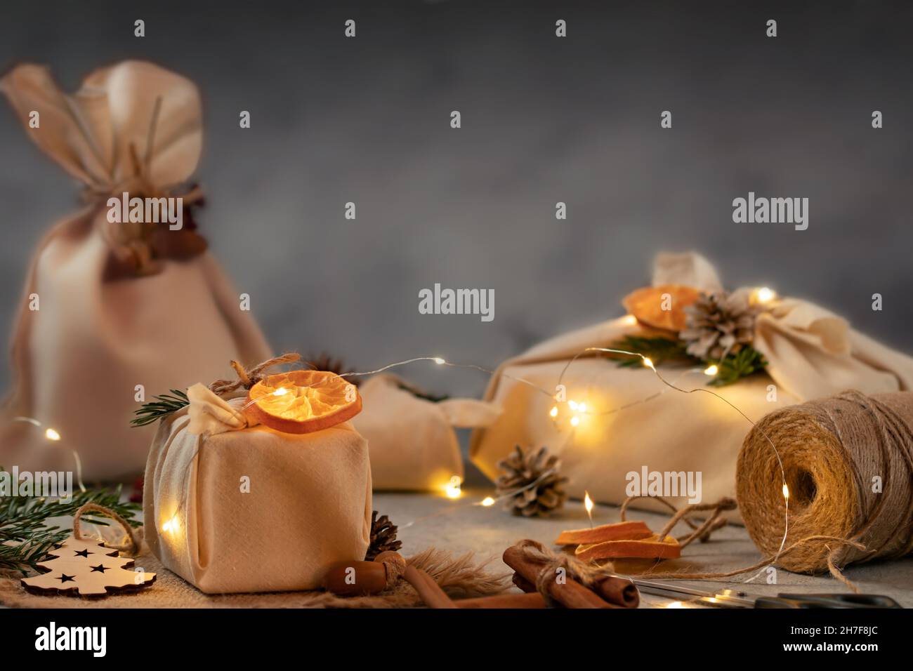 Concetto di natale senza sprechi. Confezionato in tessuto naturale regali e decorazioni da materiali naturali con luci natalizie Foto Stock